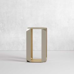 a white and gold table sitting on top of a floor next to a gray wall