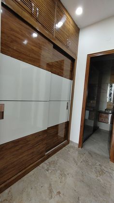 an empty room with wooden doors and white cupboards on the wall, next to a tiled floor