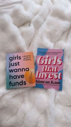 two books sitting on top of a bed next to each other in front of a white blanket