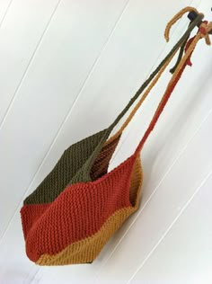 a knitted bag hanging from a hook on a white wall with wood slats