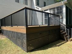 a wooden deck with black iron railings next to a house