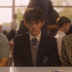 two young men sitting at a table in suits and ties