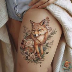 a woman's thigh with a tattoo of a fox and flowers on the side