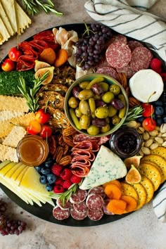 a platter filled with different types of cheeses, crackers and olives