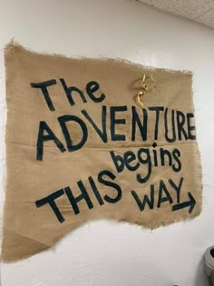 a sign on the wall that says, the adventure begins this way