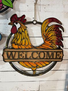 a rooster sign hanging on the side of a white wooden wall that reads, welcome