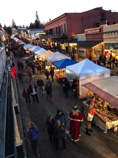 an outdoor market with people walking around and tents set up on the side of the street