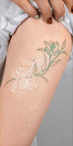 a woman's arm with a flower tattoo on her left side and green leaves