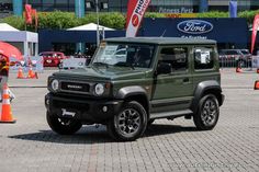 a green four door suv parked in front of an orange cone with people standing around it