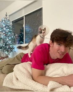 a man laying on top of a bed next to a cat