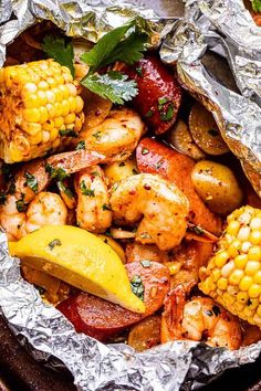 grilled shrimp, corn on the cob and potatoes in tin foil with garnish