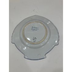 a white and gold plate with writing on the side, sitting on top of a table