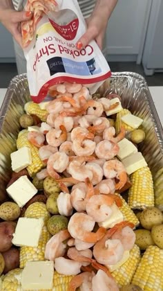 shrimp, corn and potatoes in a pan with a bag of cheese on the side