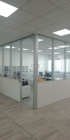 an empty office with glass walls and wood flooring