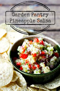 a bowl filled with salsa surrounded by tortilla chips on top of a wooden table