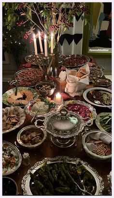 a table full of food with candles on it and plates in front of the table