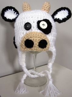 a crocheted cow hat with black eyes and ears on top of a table