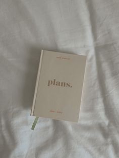 an open book sitting on top of a white sheet covered bed with the words plans