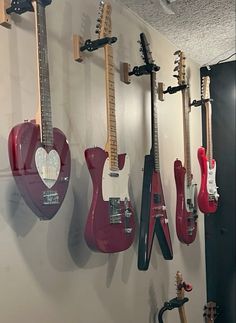 several guitars are hanging up on the wall