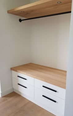 an empty room with white drawers and wooden shelves