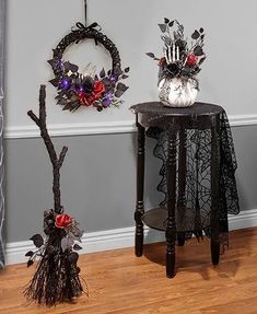 two halloween decorations sitting on top of a wooden table next to a wall mounted wreath