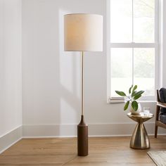 a living room scene with focus on the floor lamp and table next to the window