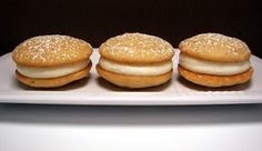 three donuts with white frosting and sprinkles sit on a plate