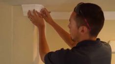 a man is painting the ceiling in his living room with white paint and a roller