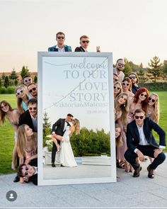 a group of people posing for a photo in front of a large sign that says welcome to our love story