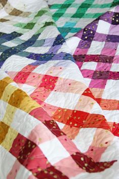 a colorful quilt is laying on top of a tablecloth that has been made with different colors and patterns