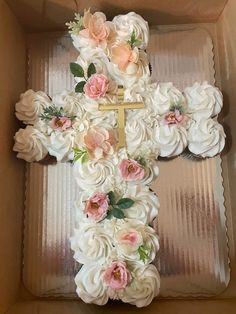 a cake in a box decorated with flowers and a cross on it's side