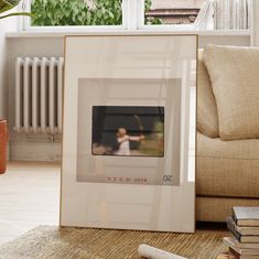 a framed photograph sitting on top of a wooden floor next to a couch and window