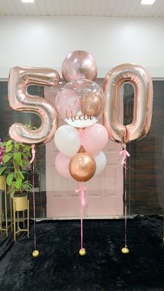 balloons and streamers in the shape of the number 50 are displayed on a black carpet