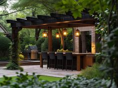 an outdoor kitchen and dining area is lit up at night with hanging lights on the roof