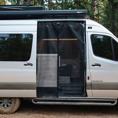 a silver van with its doors open and the door ajar is shown in front of some trees