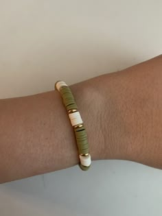 a person's arm with a bracelet made out of green and white beads on it