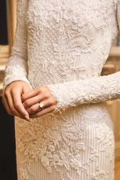 a woman in a white dress holding onto her wedding ring