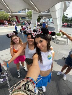 three girls in mickey mouse ears are posing for the camera with their arms around each other