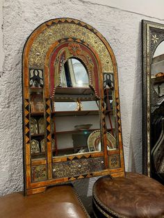 an old mirror and stool are sitting next to each other in front of a wall