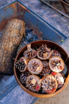 some pine cones are sitting in a bowl next to a piece of wood on the ground