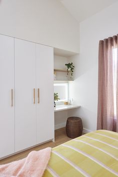 a bedroom with white cabinets and yellow bedspread on the bed, next to a window