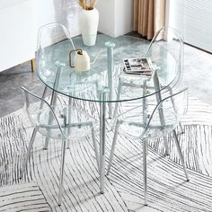 a glass table with four chairs and a white vase on the floor next to it