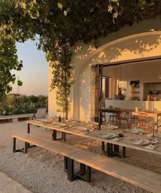 an outdoor dining area with wooden benches and tables set up for dinner on the patio