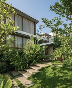 the house is surrounded by lush green trees and bushes, with stone steps leading up to it