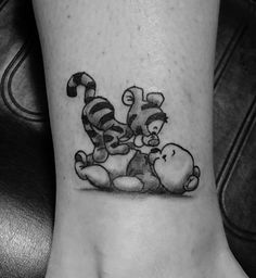 a black and white photo of winnie the pooh with tigger on her foot