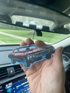 a person holding up a sticker in their hand next to the dashboard of a car