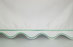 a white bed with green trim on the edge and bottom line in front of it