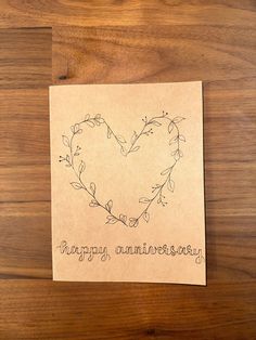 a piece of paper with the words happy anniversary written in it on top of a wooden table