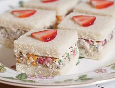 several small sandwiches on a plate with strawberries