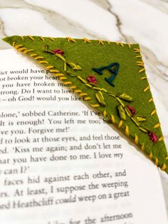 a close up of an open book with a piece of fabric on it and a green triangle